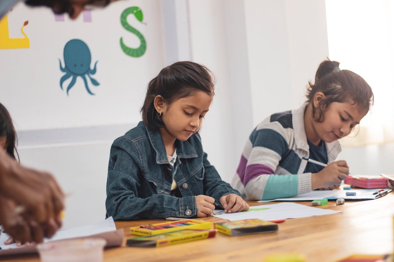 Children drawing and writing with crayons at a table